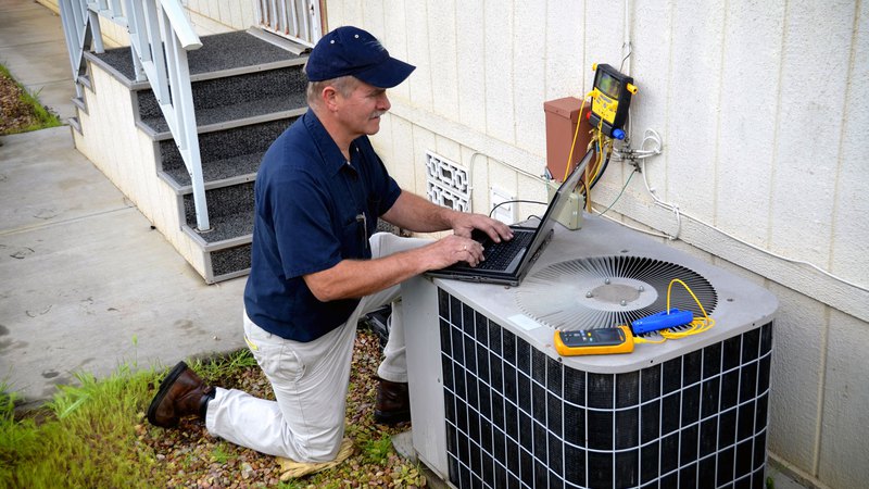 contractor using a laptop to perform air conditioning service
